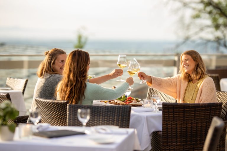 Freundinnen stoßen mit Wein an auf der Sonnenterrasse des Hofgut Laubenheimer Höhe